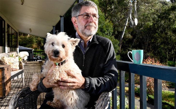 An old man with a bolognese terrier dog.