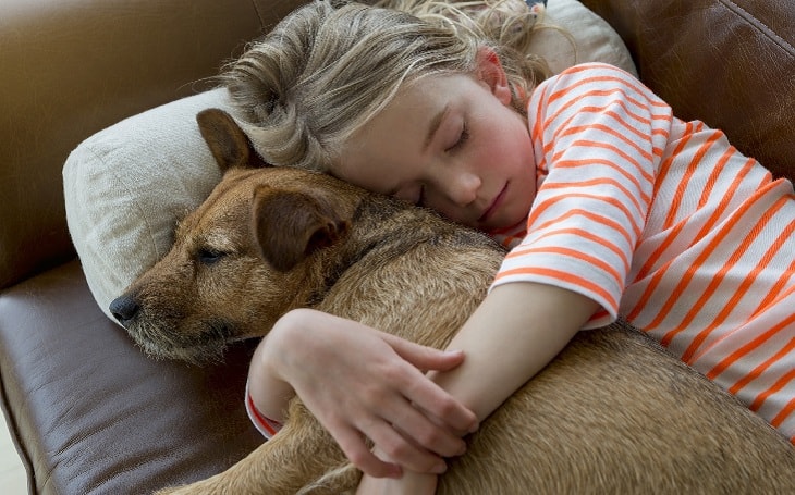 A young girl cuddling with her furry pet.
