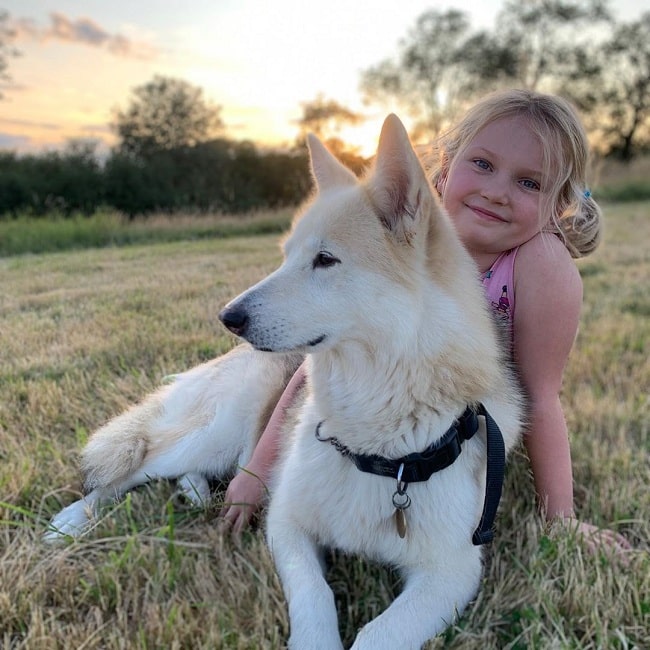 A baby girl and Utonagan relaxing on the field