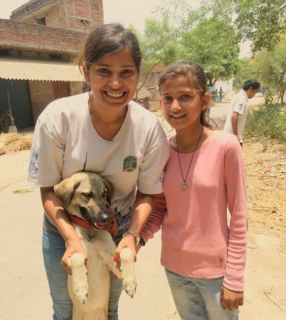 A girl and a lady playing with a Indian Pariah Dog