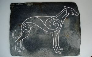 A picture of an ancient Celtic Hound crafted in a stone.